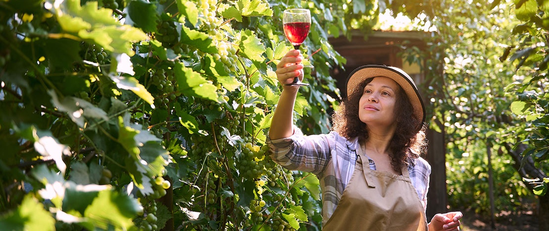 Turista con copa de vino entre viñedos