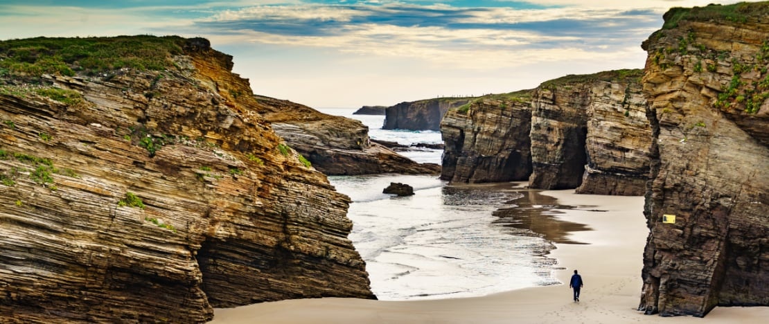 Un turista sulla spiaggia di Las Catedrales a Lugo, Galizia