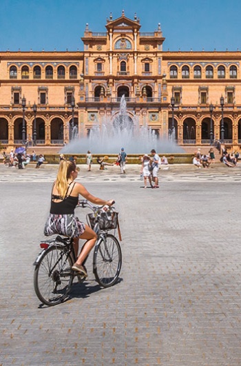 Turista in bicicletta nella Plaza de España di Siviglia